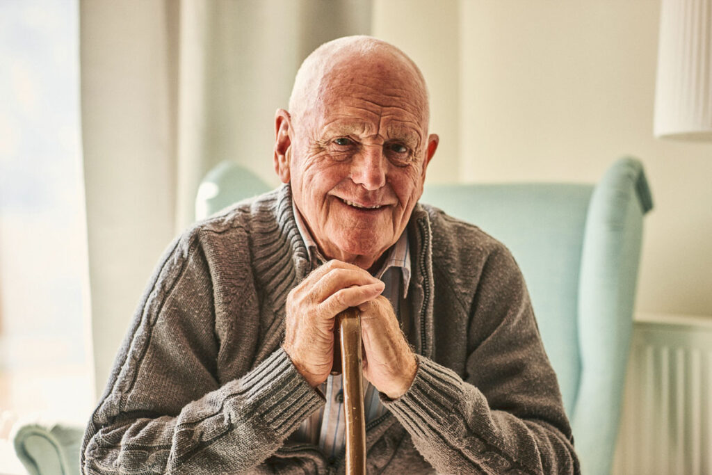 Assisted living resident elderly man leaning on cane