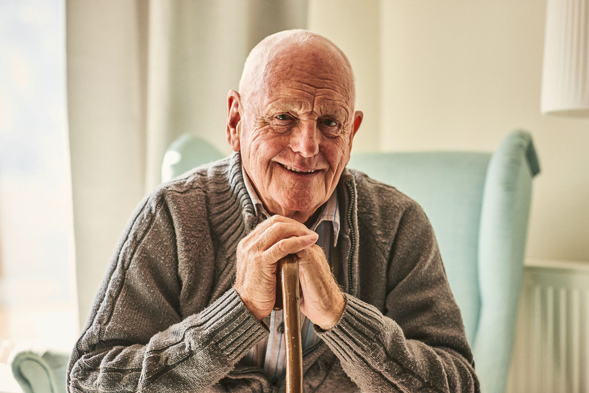 Assisted living resident elderly man leaning on cane