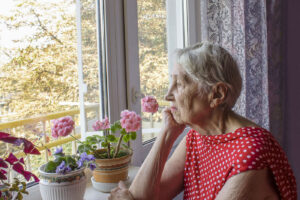 Elderly woman looking out a window from an assisted living facility in the New Orleans / Metairie area