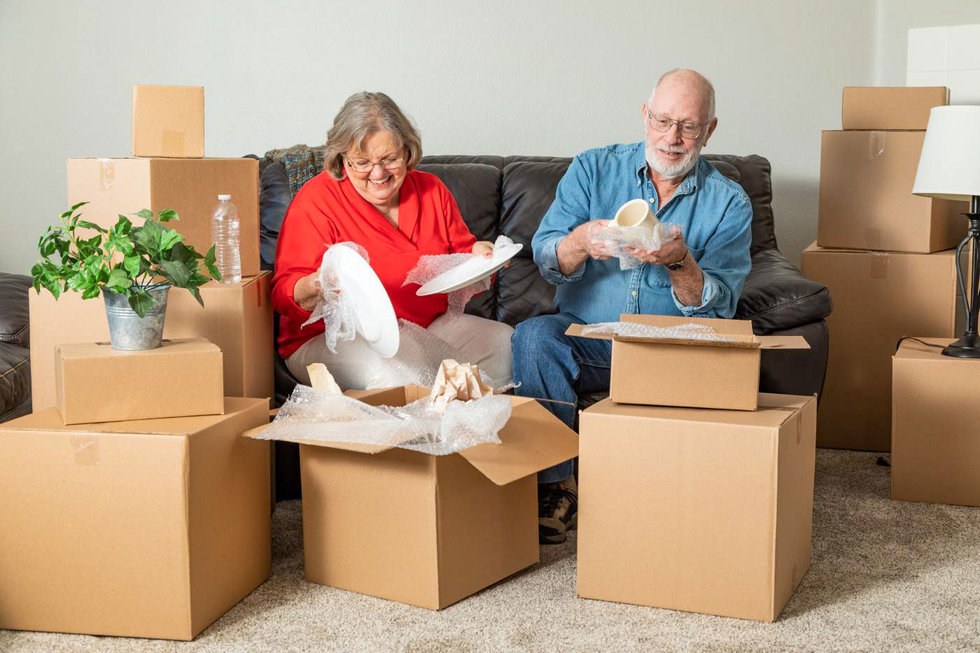 an elderly couple packs cardboard boxes -Tips and Options to Consider When Helping Aging Parents Downsize Their Home or Furnishings