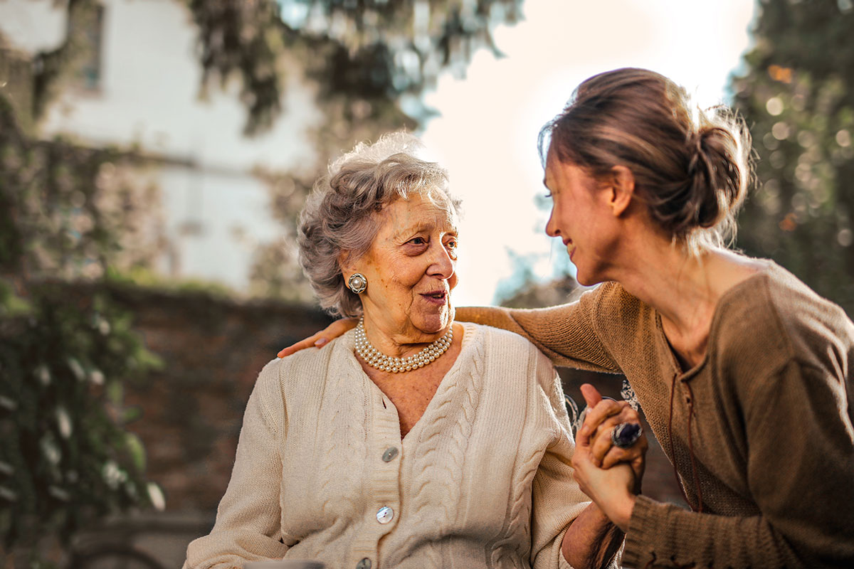 a young woman hugging her elderly mother in a garden to discuss assisted living after a fall. The woman is smiling broadly, and her mother has a look of surprise and happiness on her face The garden is full of flowers, and the sun is shining brightly The image is full of love and joy The image is a reminder of the importance of family and relationships It is also a reminder of the beauty of nature The image is well-composed and well-lit, and it captures the emotion of the moment perfectly 