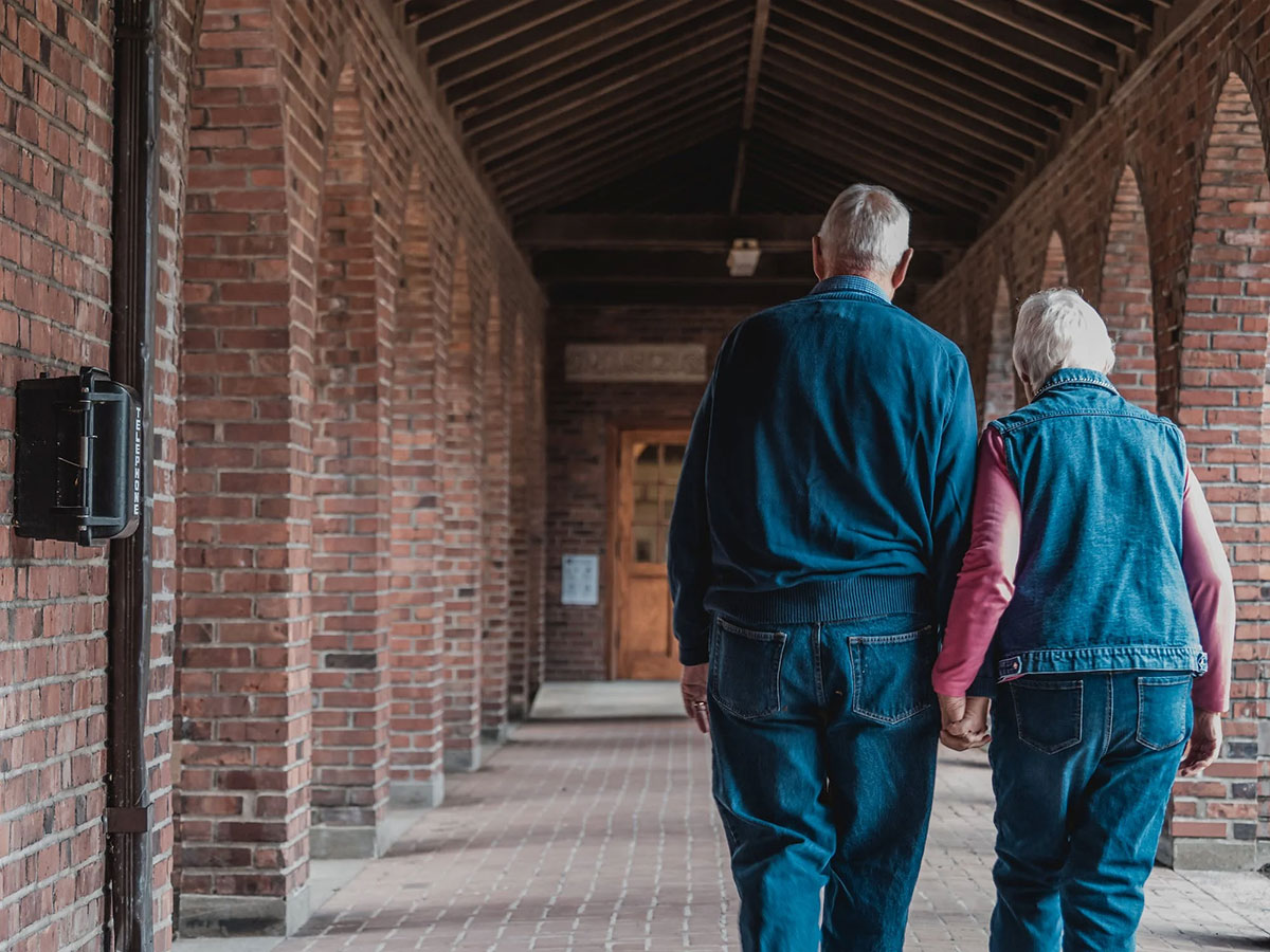 an elderly couple walking hand-in-hand down an assisted living path after a fall. The image is a reminder of the importance of love and companionship. It is also a reminder of the beauty of nature. The image is well-composed and well-lit